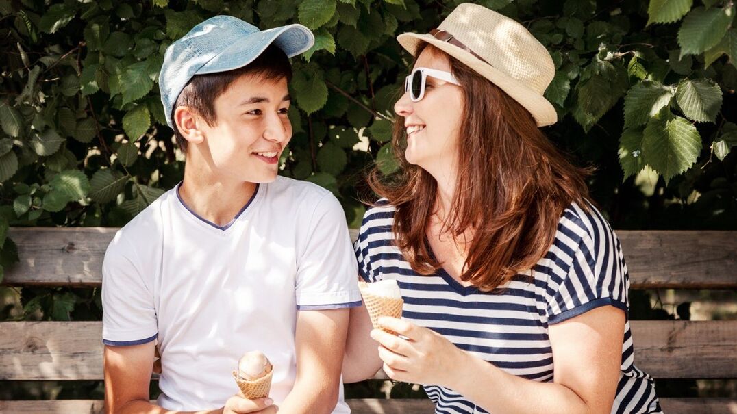 Woman and boy sitting on bench eating ice cream