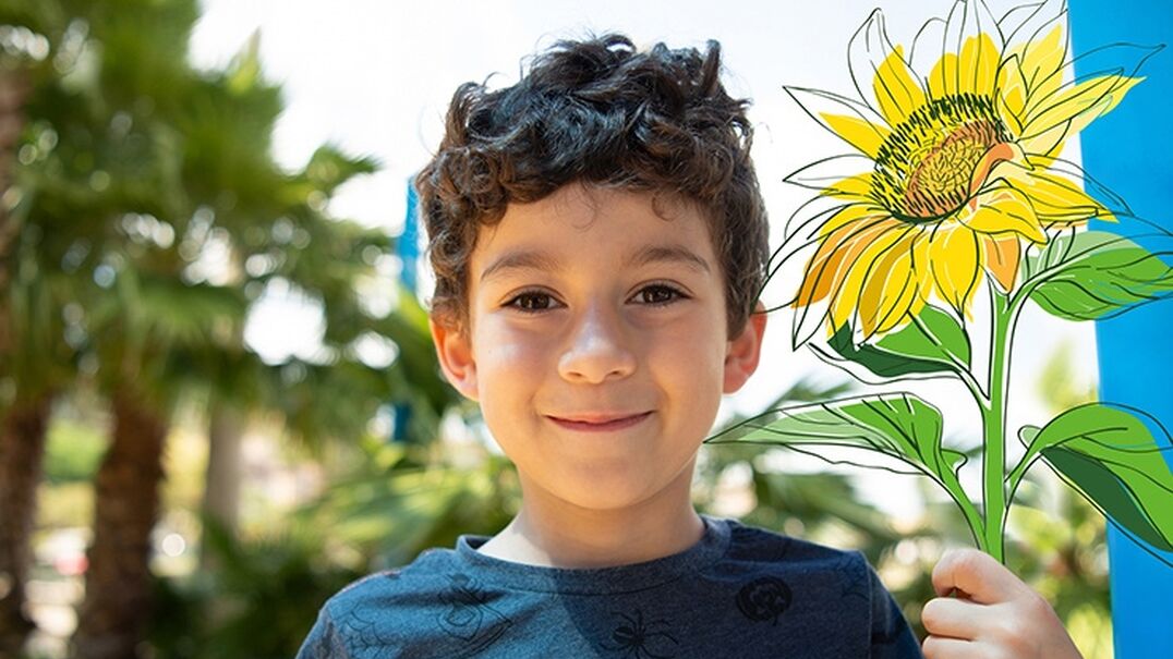 Young boy smiling holding a sunflower