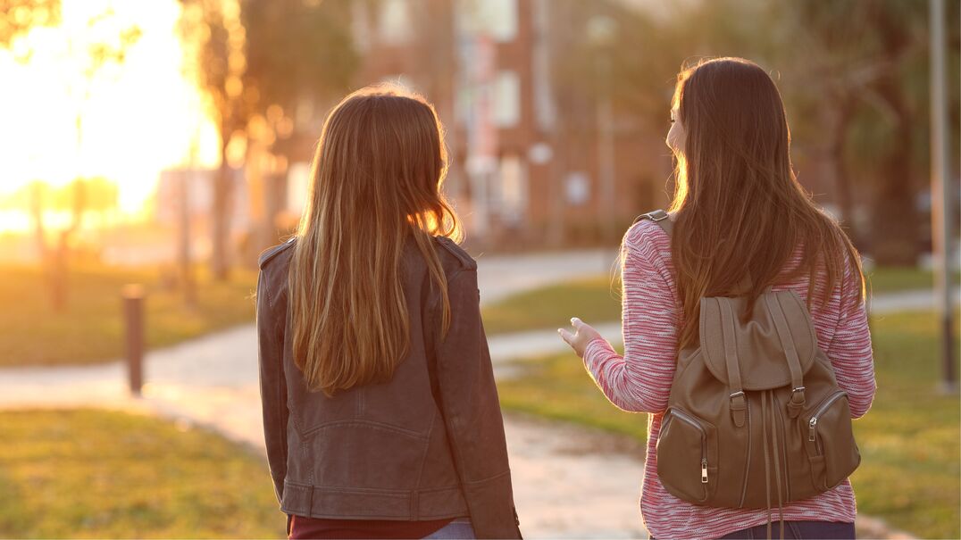 Two young people walking through a park