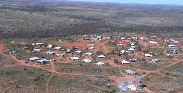 A scattering of about 30 buildings and some dirt roads in a remote community on Martu Country.