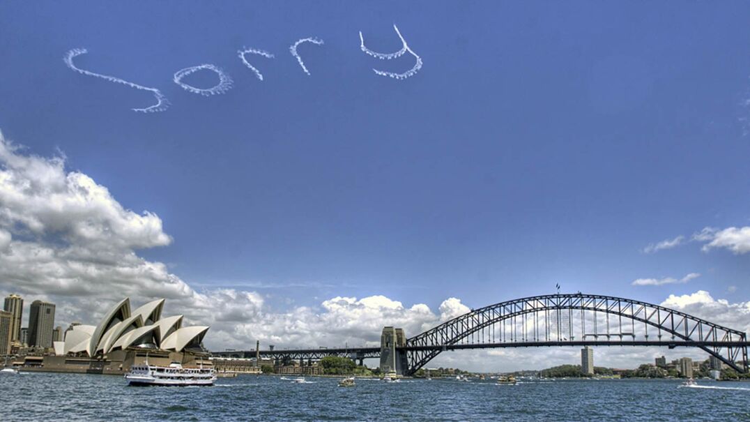 A photo of 'Sorry' written in the sky, above the Sydney Opera House and Sydney Harbour Bridge