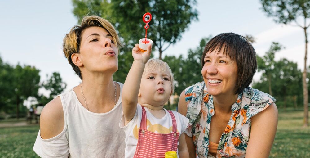 Two woman with child blowing bubbles