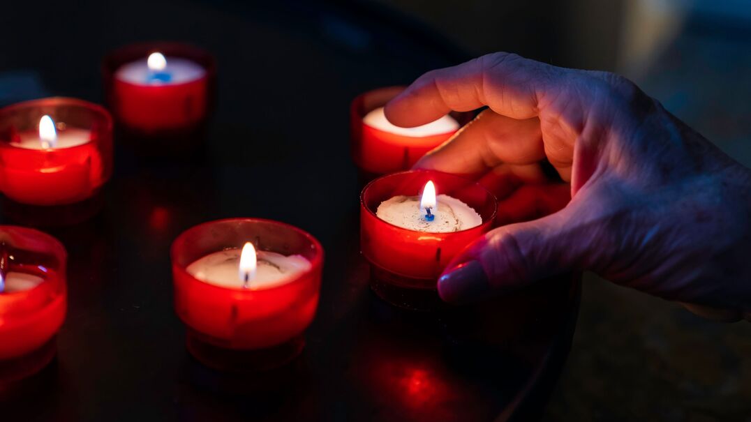 Person placing lit tealight candles on a table