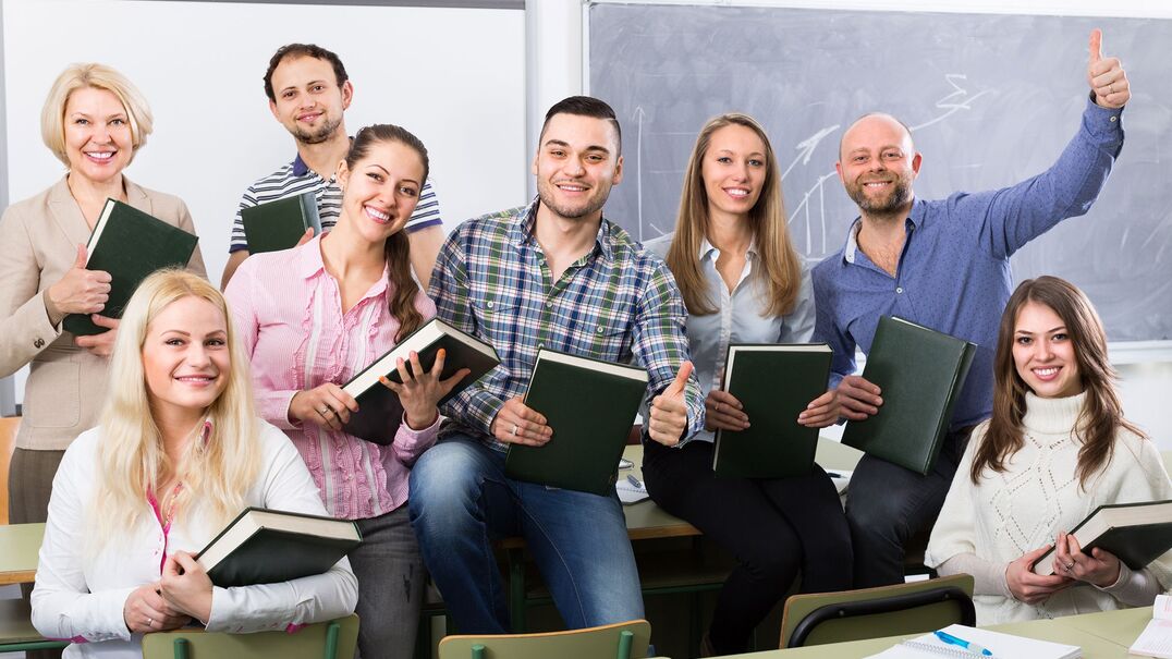 A group of teachers smiling holding books