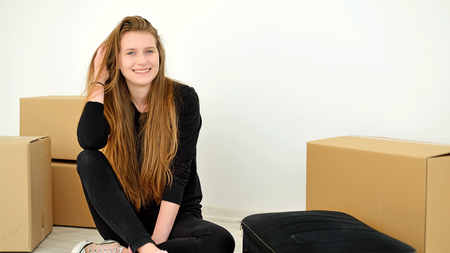 girl sitting next to boxes and suitcase smiling