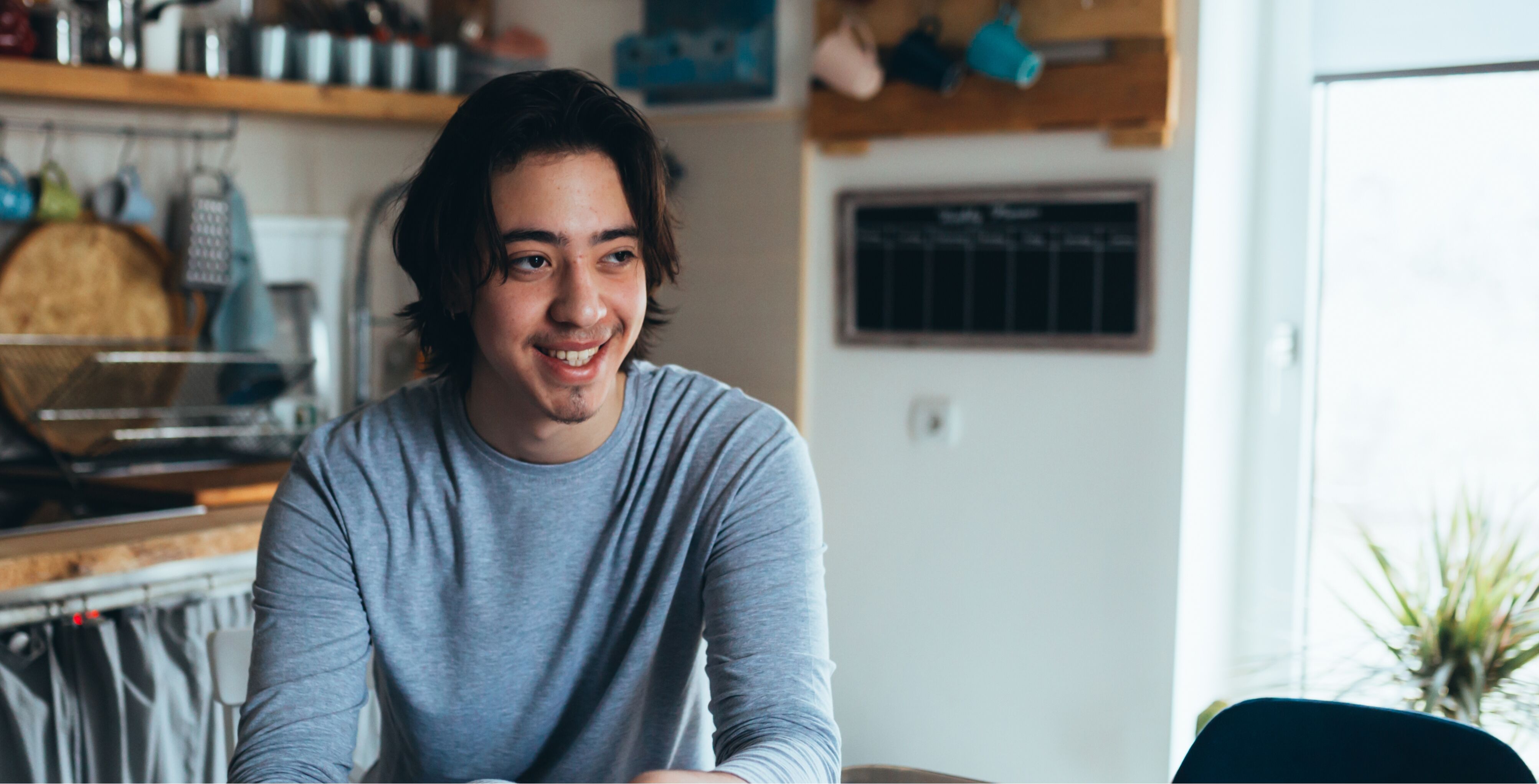 Teenage boy sitting in kitchen smiling