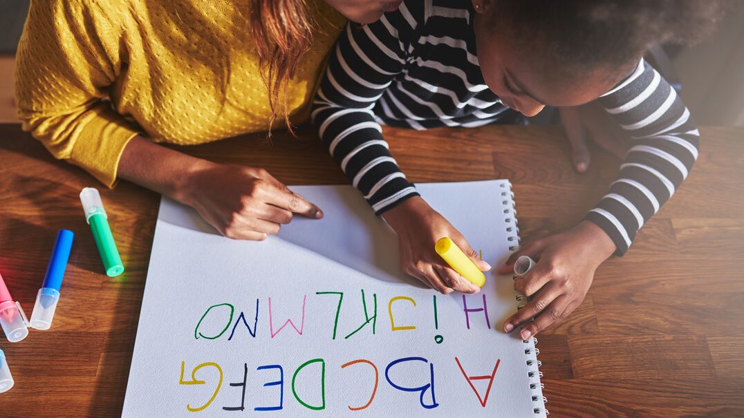 Mother and daughter writing alphabet