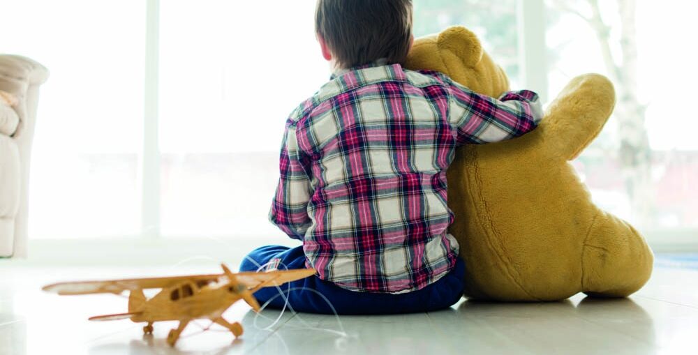 Young boy sitting on floor holding teddy bear