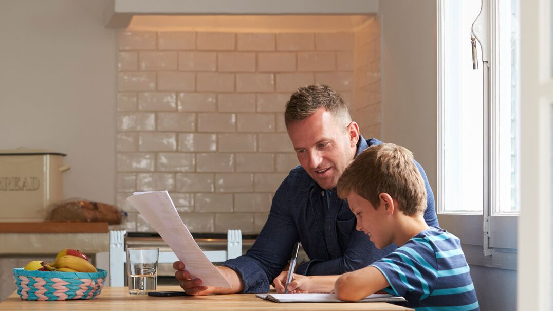 Father and son sitting in a kitchen studying