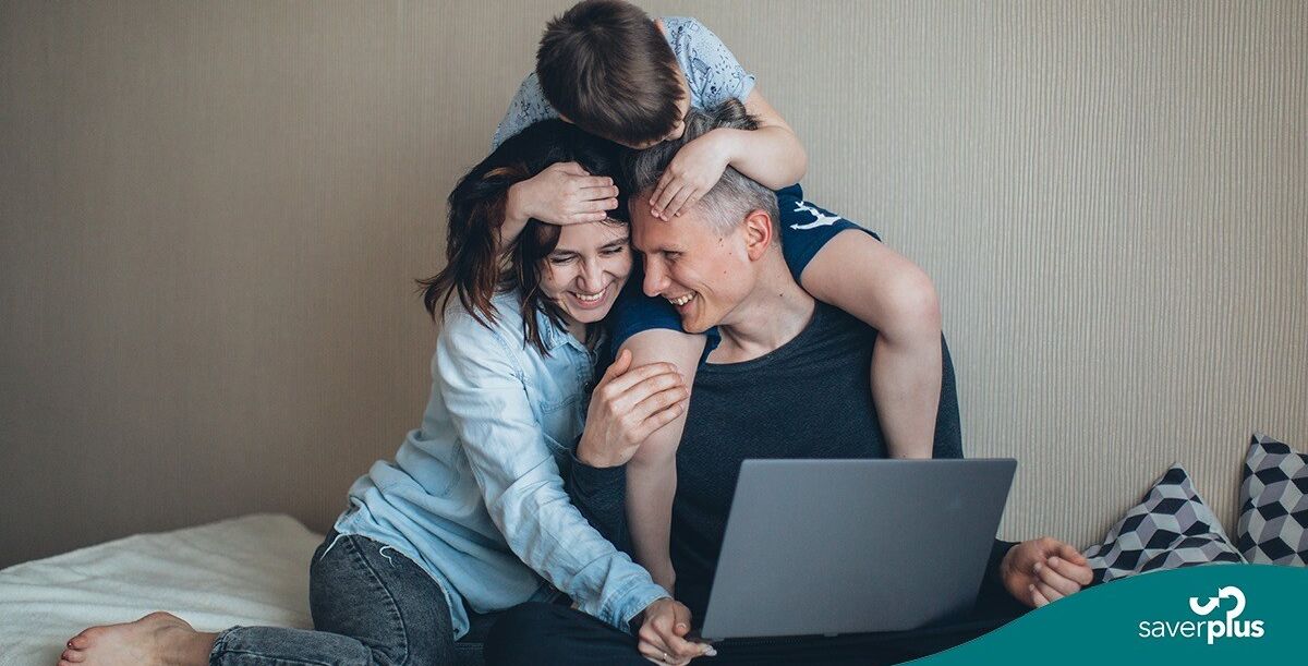 Mother and father playing with son whilst on laptop