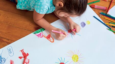 Young girl lying down colouring in
