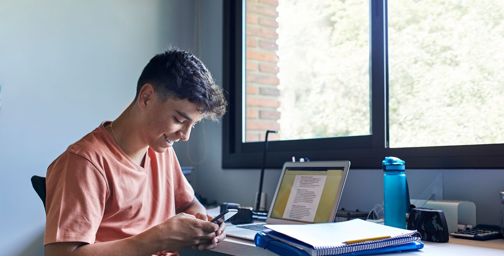 Teenage boy sitting at desk on phone