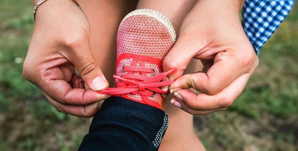 Person tying child's shoe