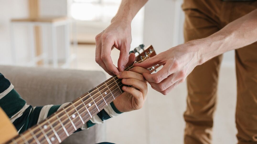 Man teaching child guitar