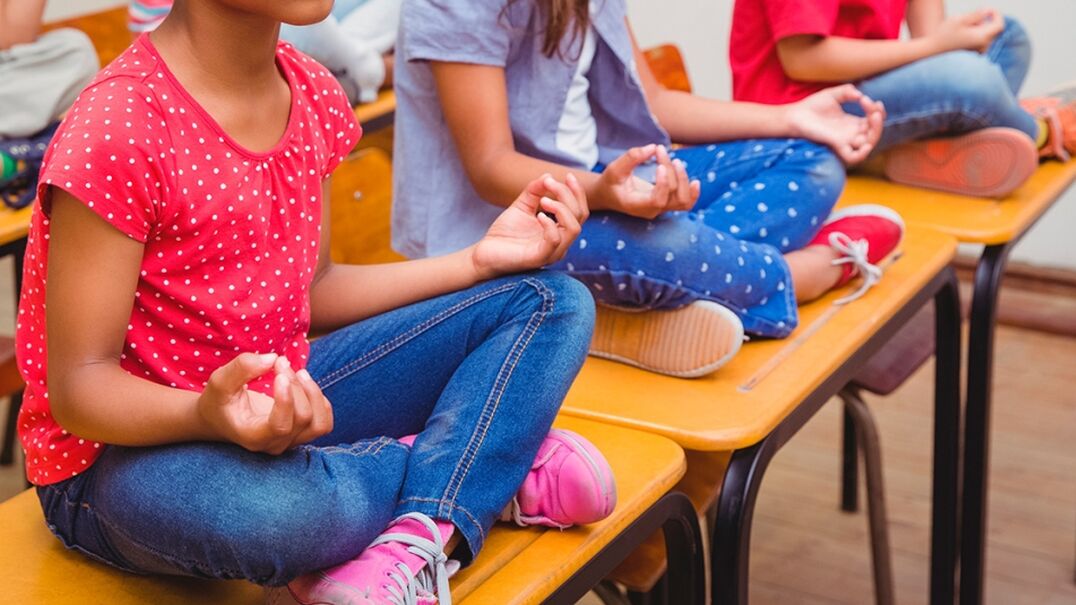 Children sitting on tables meditating