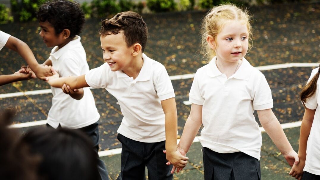 School children holding hands playing outside