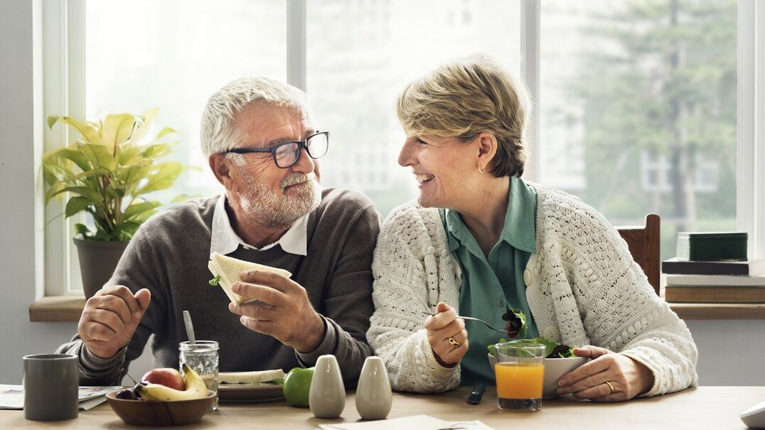 Older couple smiling at each other whilst eating