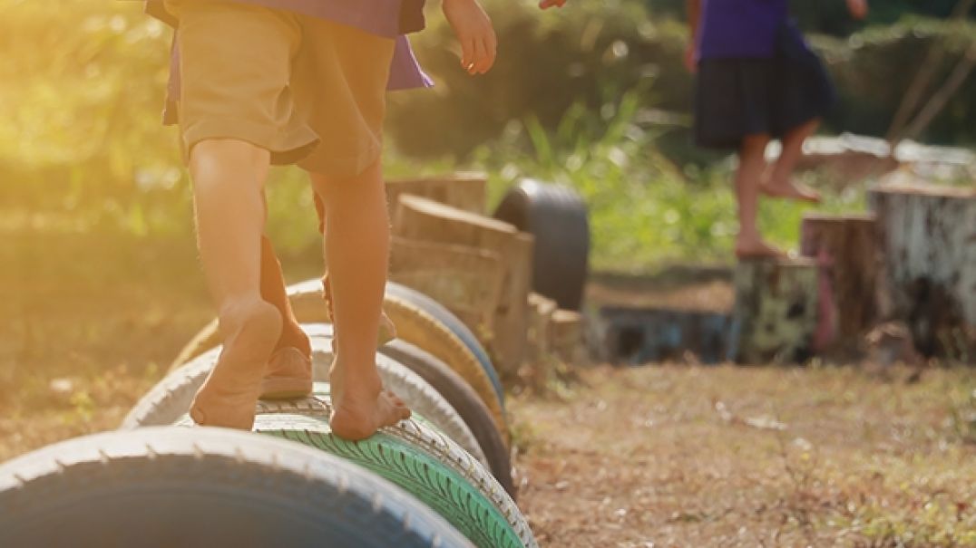 Children walking over tyres