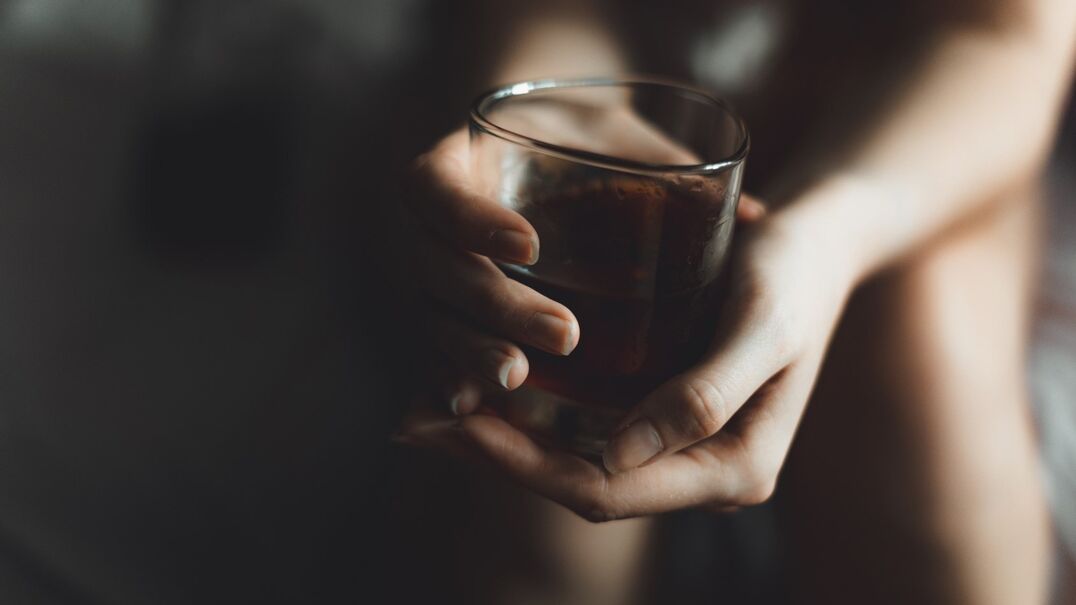 persons hands holding a glass of alcohol