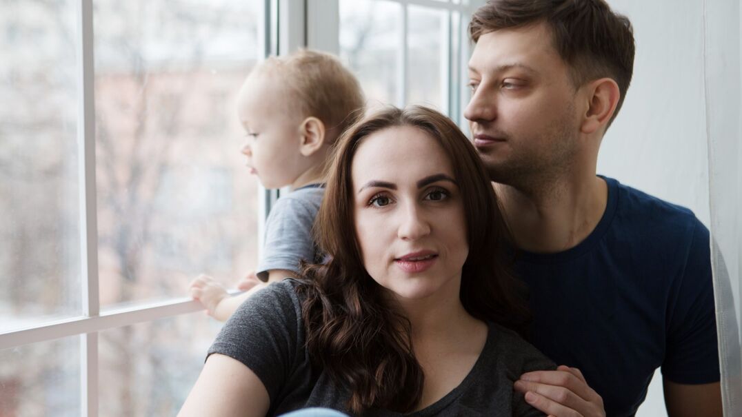 mother, father and baby sitting by a window