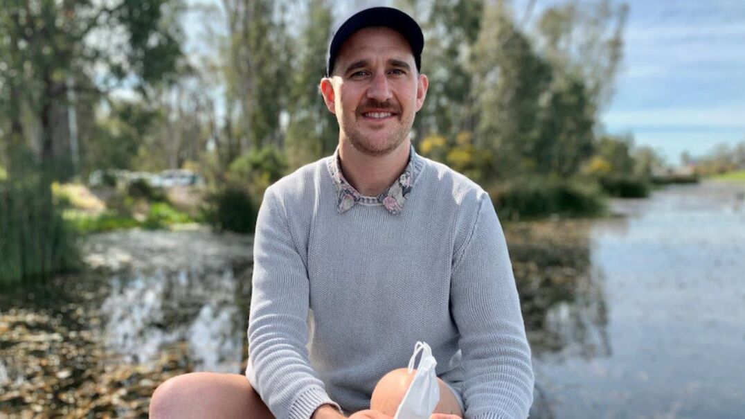 man sitting by a lake smiling