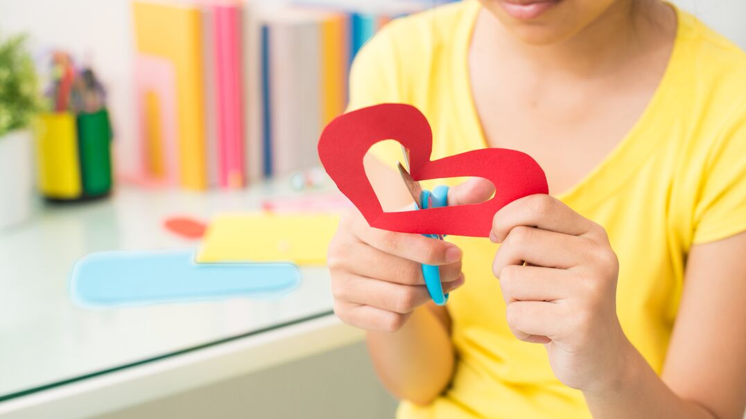 girl cutting out paper love heart