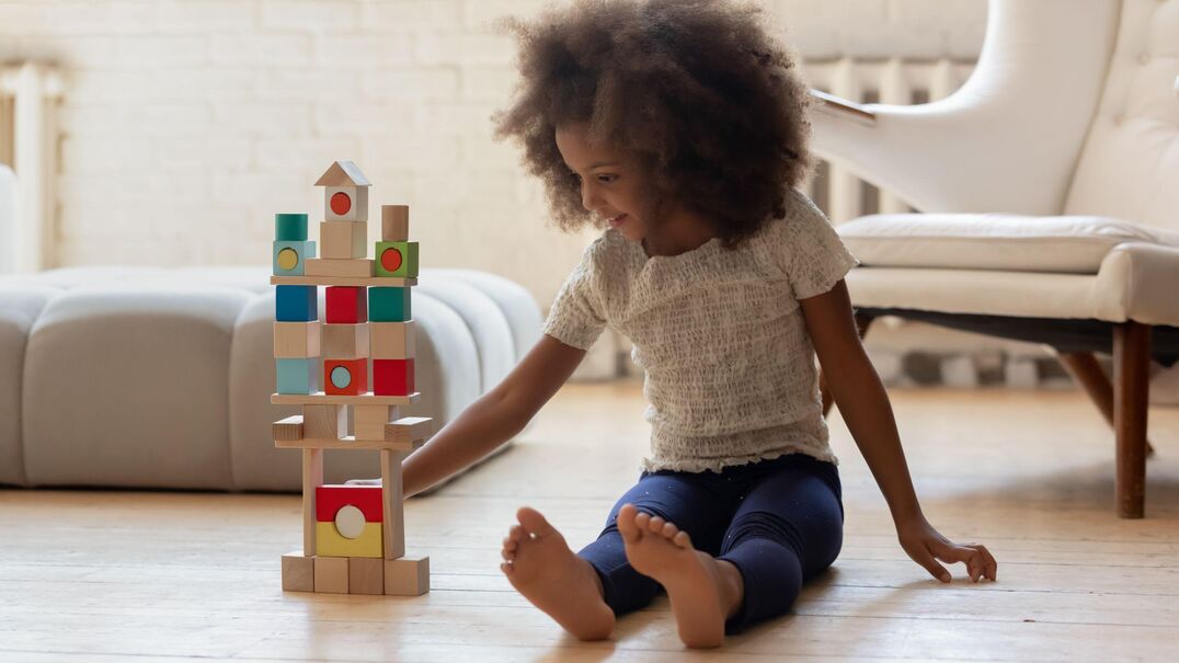 young girl sitting playing with toy blocks