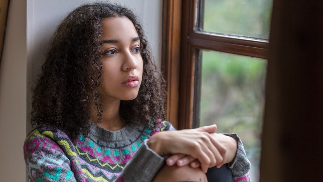teenage girl sitting by window